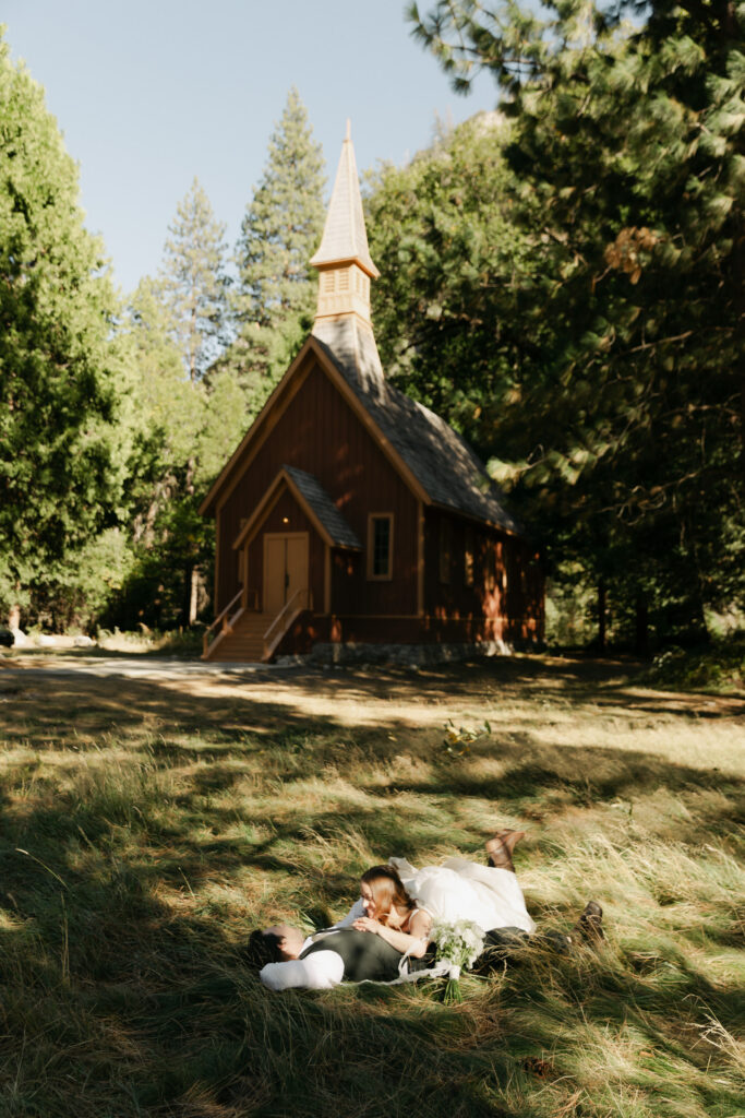 Newlyweds relaxing in the grass in front of Yosemite Valley Chapel after their micro wedding