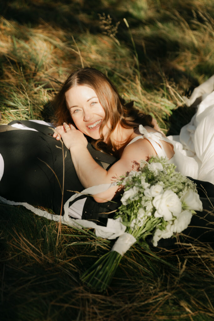 Bride and groom cuddling in the grass during their Yosemite Valley wedding portraits
