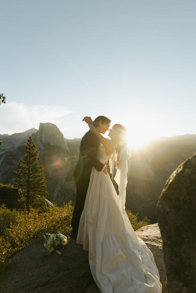 Newlyweds kissing in golden sunrise light during their Yosemite elopement at Glacier Point