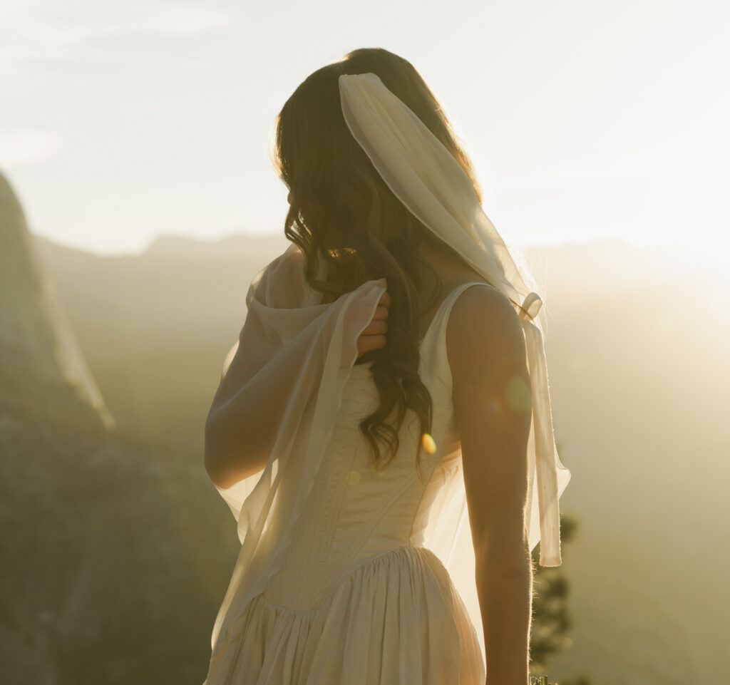 Bride glowing in soft morning light during her sunrise wedding at Glacier Point in Yosemite